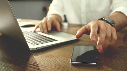 Persona en laptop y celular